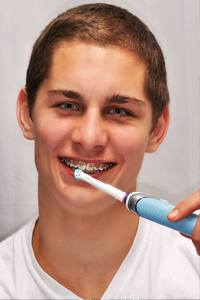 stock photo of a girl with braces brushing her teeth